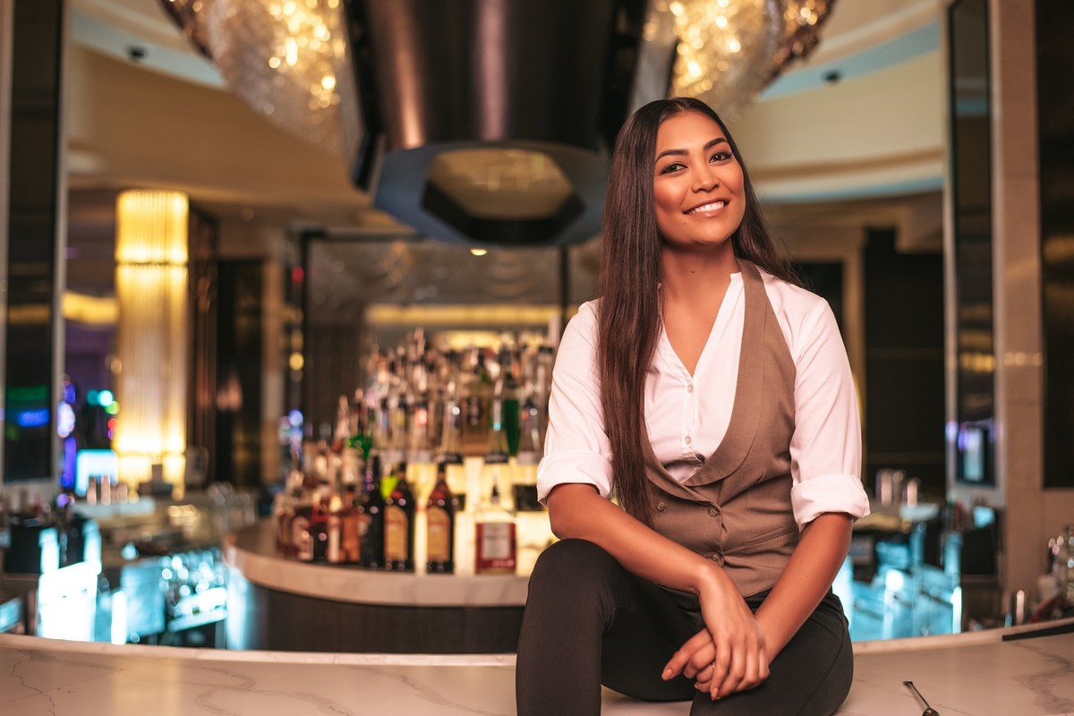 Woman bartender posing in front of the bar 